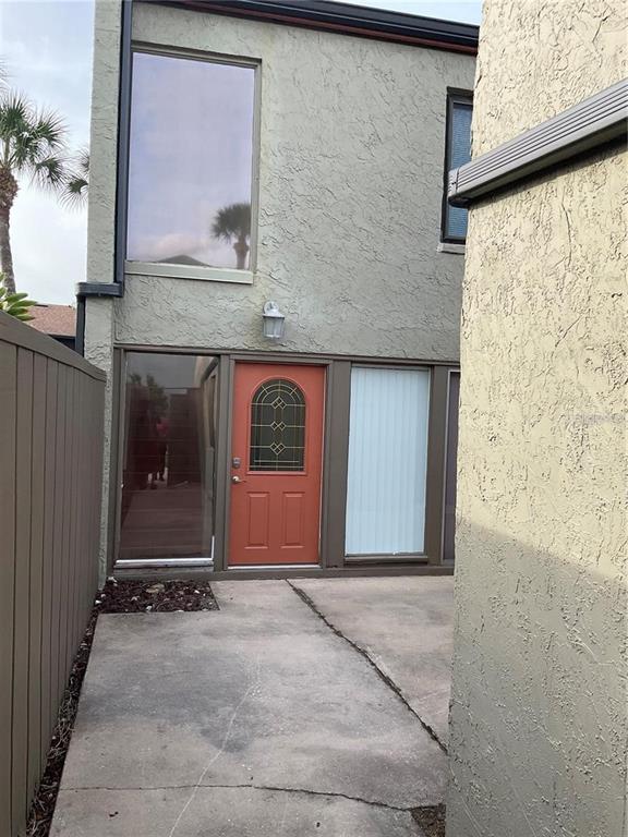 An exterior view of a home entrance featuring a terracotta door and concrete patio — 2500 21ST STREET NW UNIT 58, WINTER HAVEN, FL