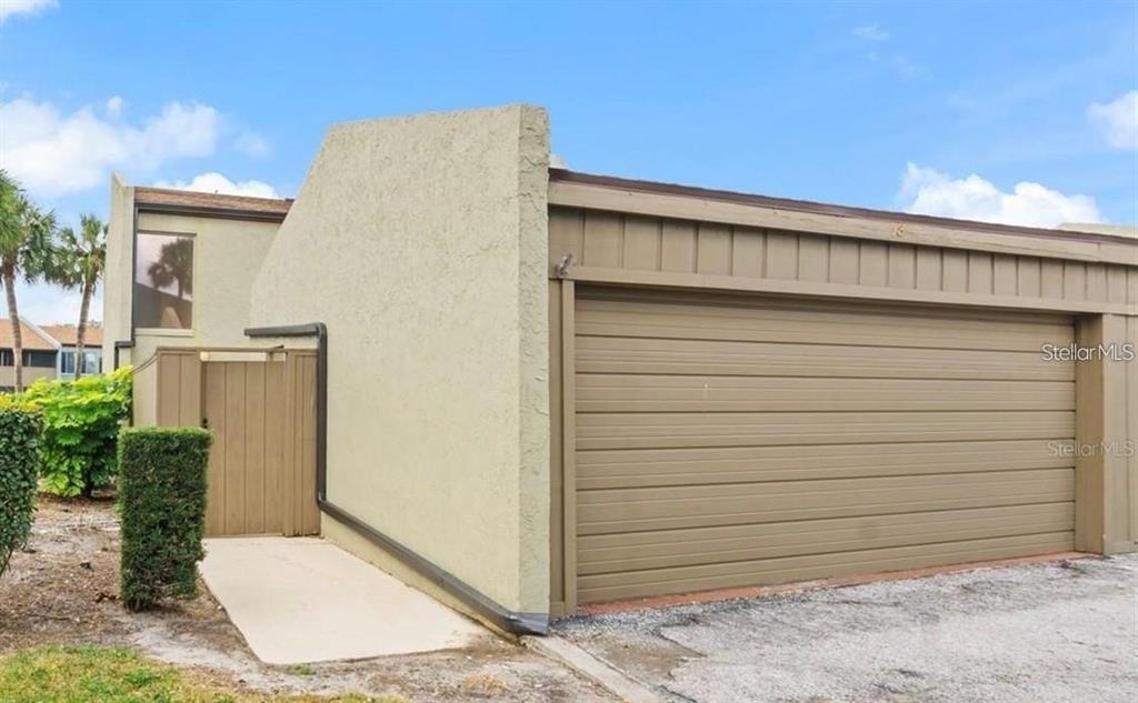 An exterior view of a tan building featuring a large brown garage door and gate — 2500 21ST STREET NW UNIT 58, WINTER HAVEN, FL