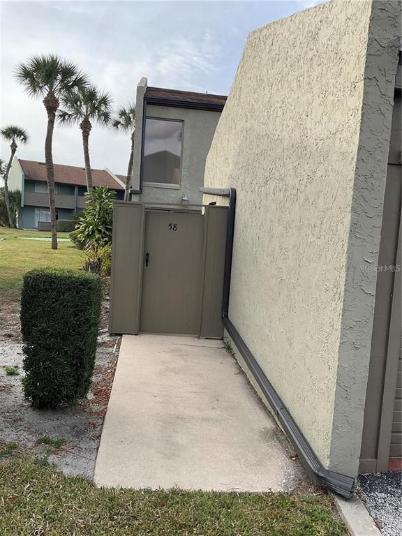 A concrete walkway leads to a gated entrance marked with the number 58 — 2500 21ST STREET NW UNIT 58, WINTER HAVEN, FL