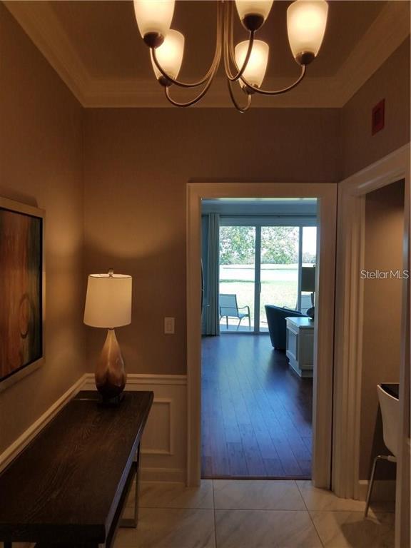 A hallway with a console table and chandelier leads to a room with a view — 51 MAC EWEN DRIVE UNIT 8, OSPREY, FL