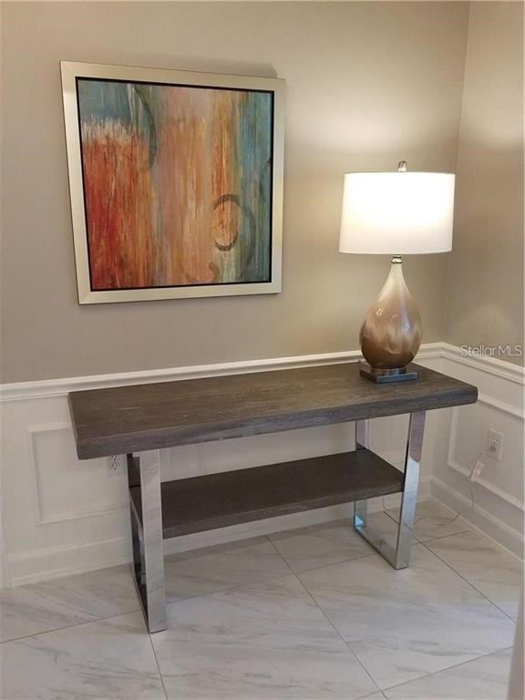 A console table with a lamp and abstract art sits against a paneled wall — 51 MAC EWEN DRIVE UNIT 8, OSPREY, FL