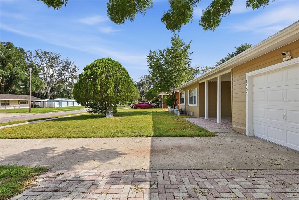 A tan house with a white garage door and a paved driveway sits on a lawn — 4302 MEADOWBROOK AVENUE, ORLANDO, FL