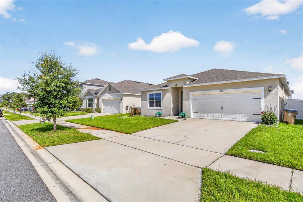 A suburban street view showing two single-story houses with driveways and manicured lawns — 1959 CACUTTA WAY, KISSIMMEE, FL